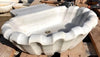 Pila bautismal de mármol con forma de concha.