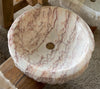 Lavabo redondo de mármol rosa.