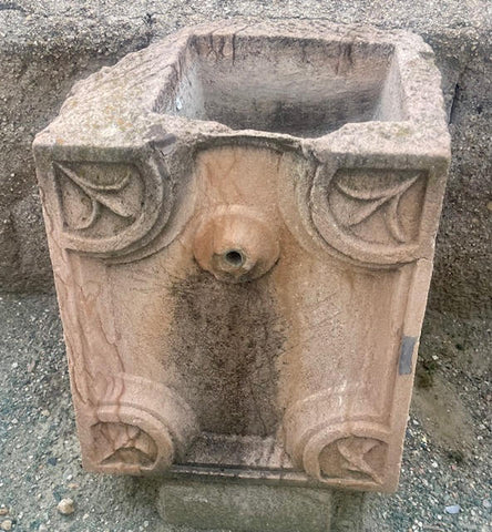 Fuente de piedra caliza rojiza de pared