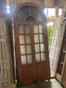 Puerta madera de medio arco con cristales.